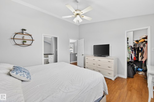 Bedroom with light wood-style flooring, a walk in closet, ceiling fan, and connected bathroom - 24 Olmstead Court, St. Albert, AB - Indoor Photo Showing Bedroom