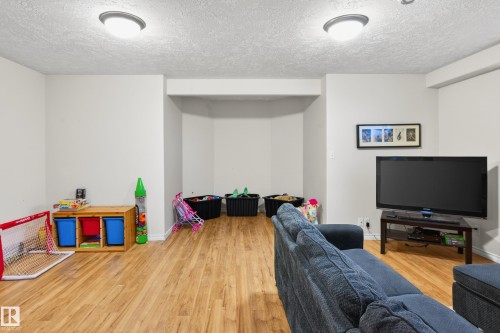 Recreation room with light wood-style floors and a textured ceiling - 24 Olmstead Court, St. Albert, AB - Indoor