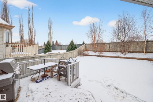 Yard layered in snow featuring outdoor dining space, a wooden deck, and a fenced backyard - 24 Olmstead Court, St. Albert, AB - Outdoor