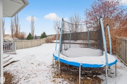 Yard covered in snow with a fenced backyard and a trampoline - 