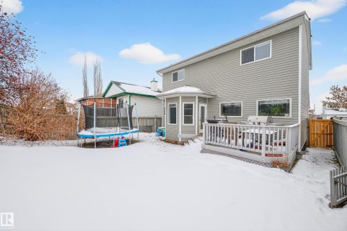 Snow covered house featuring a trampoline, a wooden deck, a fenced backyard, and a gate - 24 Olmstead Court, St. Albert, AB - Outdoor With Exterior