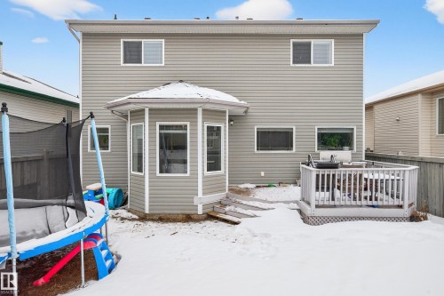 Snow covered rear of property featuring a trampoline and a wooden deck - 24 Olmstead Court, St. Albert, AB - Outdoor With Exterior
