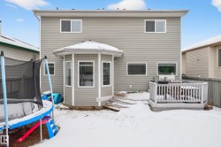 Snow covered rear of property featuring a trampoline and a wooden deck - 