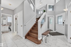 Entrance foyer featuring light marble finish flooring, stairway, and a high ceiling - 