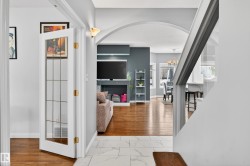 Hallway with arched walkways, light marble finish flooring, and a chandelier - 