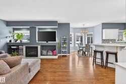 Living area with a glass covered fireplace, light wood-style flooring, and a chandelier - 