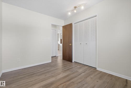 Unfurnished bedroom featuring wood finished floors, a closet, and a textured ceiling - 1704 89 Street, Edmonton, AB - Indoor Photo Showing Other Room