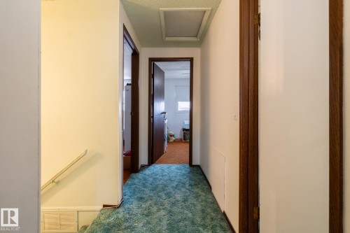 Hallway with dark carpet, an upstairs landing, a textured ceiling, and attic access - 1346 Lakewood Road W, Edmonton, AB - Indoor Photo Showing Other Room