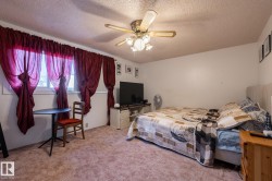 Bedroom with a textured ceiling, ceiling fan, and light colored carpet - 