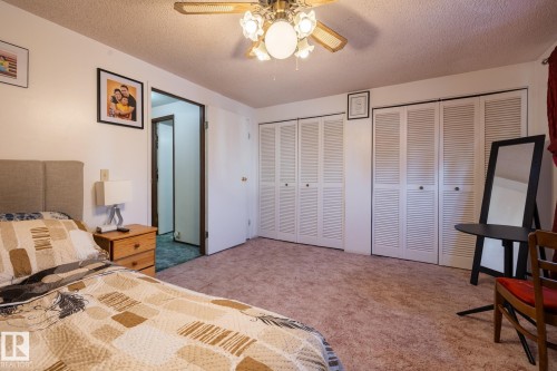 Bedroom with multiple closets, a textured ceiling, light carpet, and ceiling fan - 1346 Lakewood Road W, Edmonton, AB - Indoor Photo Showing Bedroom