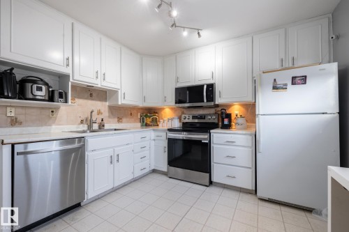 Kitchen featuring appliances with stainless steel finishes, white cabinetry, decorative backsplash, and light tile patterned flooring - 1346 Lakewood Road W, Edmonton, AB - Indoor Photo Showing Kitchen