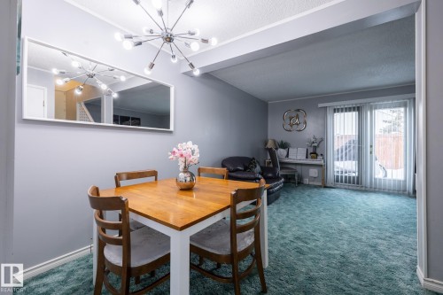 Dining space with dark carpet, a chandelier, and a textured ceiling - 1346 Lakewood Road W, Edmonton, AB - Indoor Photo Showing Dining Room