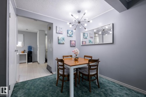 Dining space with a textured ceiling, a chandelier, light colored carpet, and light tile patterned floors - 1346 Lakewood Road W, Edmonton, AB - Indoor Photo Showing Dining Room