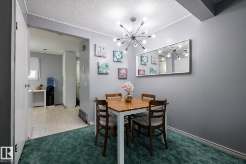 Dining area with a textured ceiling, a chandelier, light carpet, and light tile patterned flooring - 1346 Lakewood Road W, Edmonton, AB - Indoor Photo Showing Dining Room