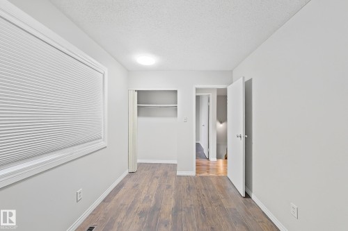 Unfurnished bedroom with a textured ceiling, dark wood-style floors, and a closet - 24 3812 20 Avenue, Edmonton, AB - Indoor Photo Showing Other Room