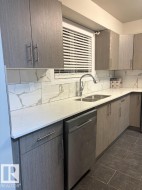 Kitchen featuring light stone countertops, dishwasher, tasteful backsplash, and modern cabinets - 