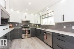 Kitchen featuring white cabinets, gray cabinetry, appliances with stainless steel finishes, modern cabinets, and recessed lighting - 
