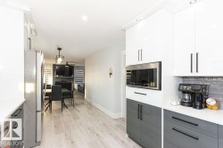 Kitchen with gray cabinets, white cabinets, appliances with stainless steel finishes, modern cabinets, and light wood-style floors - 