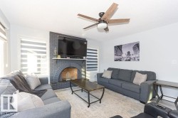 Living area featuring a textured ceiling, a brick fireplace, and ceiling fan - 
