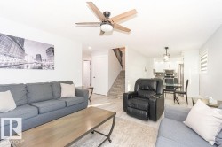Living room with light wood-type flooring, stairs, and ceiling fan - 