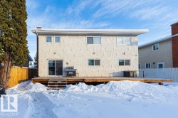 Snow covered rear of property featuring a wooden deck and stucco siding - 