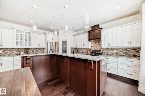 Kitchen with ornamental molding, white cabinetry, glass insert cabinets, decorative light fixtures, and appliances with stainless steel finishes - 6 Wade Avenue, Leduc, AB - Indoor Photo Showing Kitchen With Upgraded Kitchen