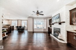 Living room with a fireplace, a textured ceiling, dark wood-type flooring, ceiling fan, and recessed lighting - 