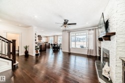 Living area with a stone fireplace, stairway, dark wood finished floors, a textured ceiling, and ceiling fan - 