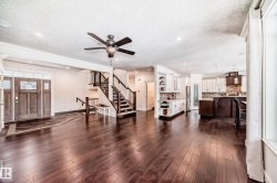 Living area with stairway, a textured ceiling, dark wood-type flooring, recessed lighting, and a ceiling fan - 