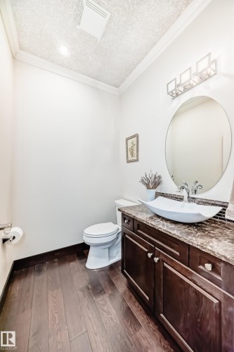 Half bathroom with vanity, dark wood finished floors, crown molding, and a textured ceiling - 6 Wade Avenue, Leduc, AB - Indoor Photo Showing Bathroom