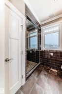 Bathroom with ornamental molding, a shower stall, and dark tile patterned floors - 