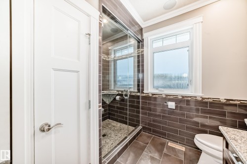 Bathroom with a shower stall, crown molding, vanity, dark tile patterned flooring, and tile walls - 6 Wade Avenue, Leduc, AB - Indoor Photo Showing Bathroom