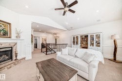 Living area featuring vaulted ceiling, a glass covered fireplace, light colored carpet, a chandelier, and recessed lighting - 
