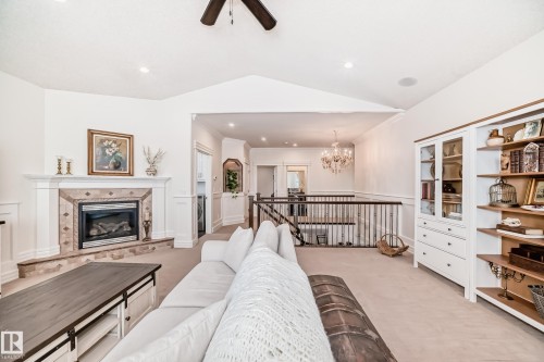 Living area featuring light carpet, a tiled fireplace, lofted ceiling, a chandelier, and ceiling fan - 6 Wade Avenue, Leduc, AB - Indoor Photo Showing Living Room With Fireplace