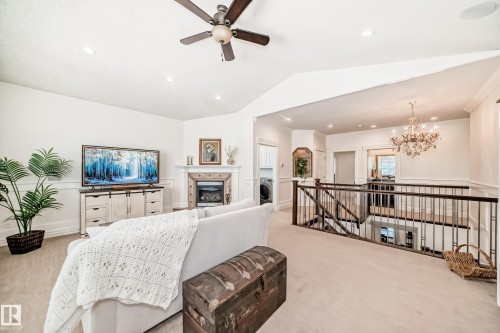 Carpeted living room with a glass covered fireplace, vaulted ceiling, recessed lighting, a ceiling fan, and washer / dryer - 6 Wade Avenue, Leduc, AB - Indoor Photo Showing Living Room With Fireplace