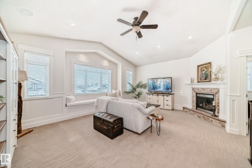 Living area featuring a decorative wall, a ceiling fan, a fireplace, light carpet, and vaulted ceiling - 6 Wade Avenue, Leduc, AB - Indoor Photo Showing Living Room With Fireplace