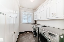 Laundry room featuring crown molding, washing machine and clothes dryer, dark tile patterned flooring, and cabinet space - 