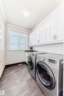 Laundry room featuring cabinet space, ornamental molding, washing machine and dryer, and light tile patterned flooring - 