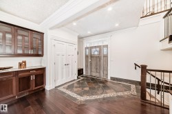 Entryway featuring ornamental molding, dark wood-style floors, inlaid floor details, and a textured ceiling - 