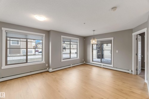 Unfurnished dining area with baseboard heating, light wood finished floors, and a textured ceiling - 101 3670 139 Avenue, Edmonton, AB - Indoor Photo Showing Other Room