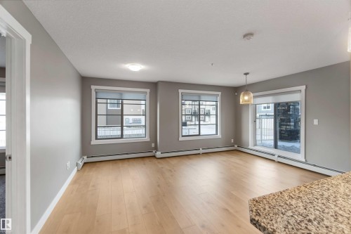 Unfurnished dining area featuring light wood-type flooring and a baseboard radiator - 101 3670 139 Avenue, Edmonton, AB - Indoor Photo Showing Other Room