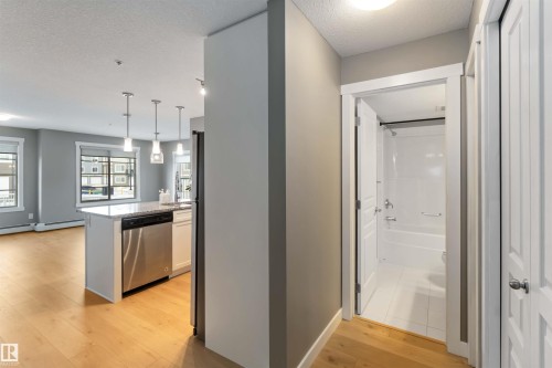 Hallway with light wood-type flooring and a textured ceiling - 101 3670 139 Avenue, Edmonton, AB - Indoor