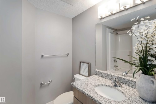 Full bathroom featuring vanity, washtub / shower combination, and a textured ceiling - 101 3670 139 Avenue, Edmonton, AB - Indoor Photo Showing Bathroom