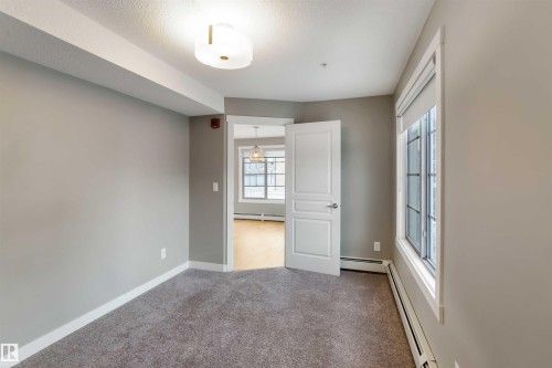 Unfurnished bedroom with a baseboard radiator, light colored carpet, and a textured ceiling - 101 3670 139 Avenue, Edmonton, AB - Indoor Photo Showing Other Room