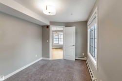Unfurnished bedroom with a baseboard radiator, light colored carpet, and a textured ceiling - 