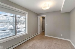 Empty room featuring a baseboard radiator, light colored carpet, and a textured ceiling - 