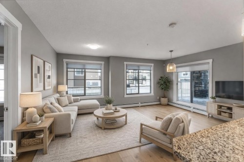 Living room with light wood-type flooring and baseboard heating - 101 3670 139 Avenue, Edmonton, AB - Indoor Photo Showing Living Room