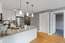 Kitchen featuring a peninsula, white cabinetry, tasteful backsplash, light stone counters, and stainless steel appliances - 