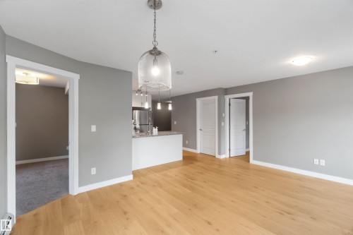 Unfurnished living room featuring light wood-style floors and a baseboard heating unit - 101 3670 139 Avenue, Edmonton, AB - Indoor