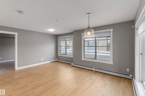 Unfurnished dining area featuring a baseboard radiator and light wood-style floors - 101 3670 139 Avenue, Edmonton, AB - Indoor Photo Showing Other Room